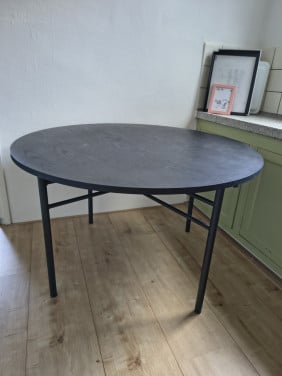 Prachtige ronde houten zwarte eettafel met metalen poten.