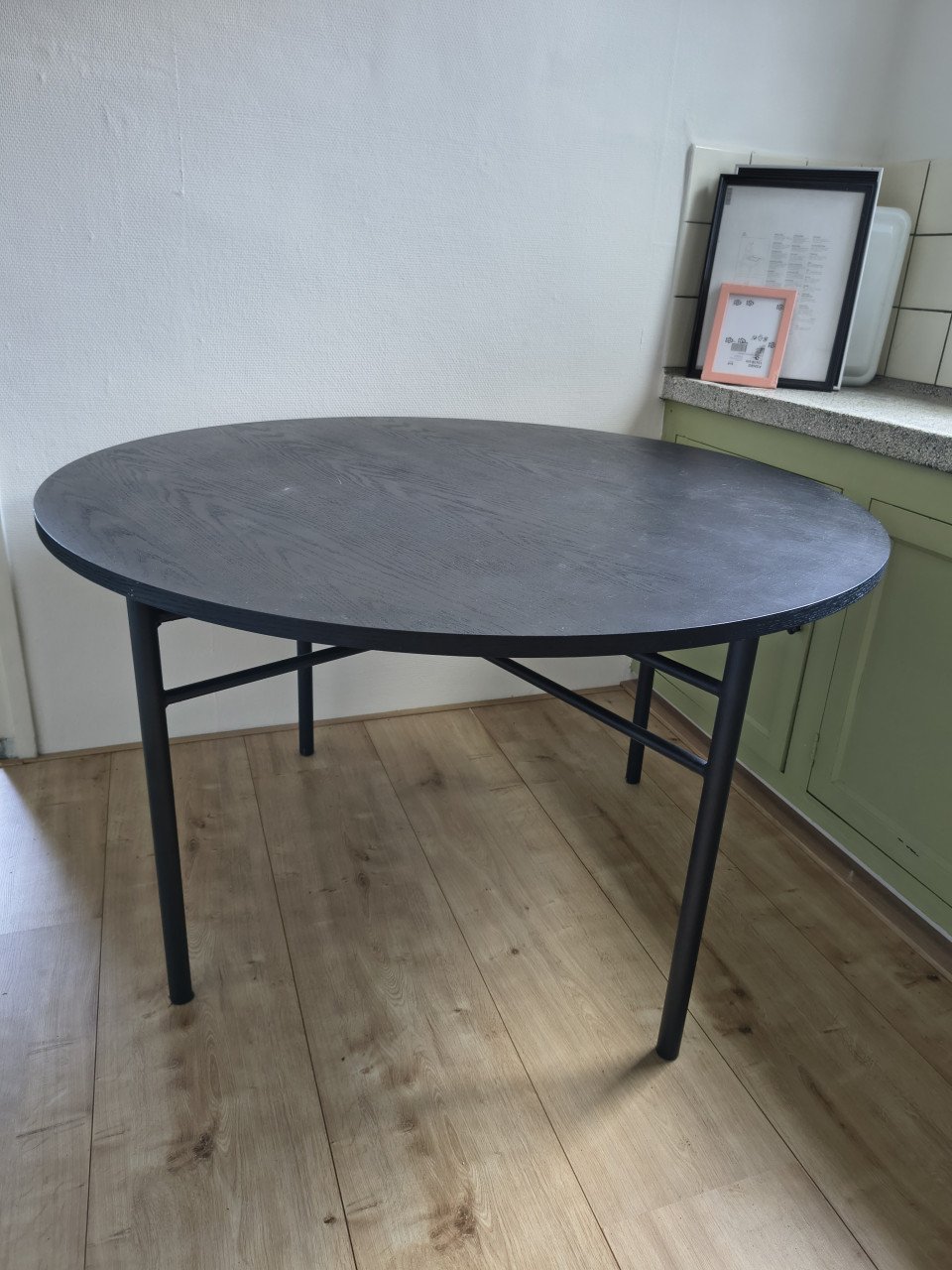 Prachtige ronde houten zwarte eettafel met metalen poten.