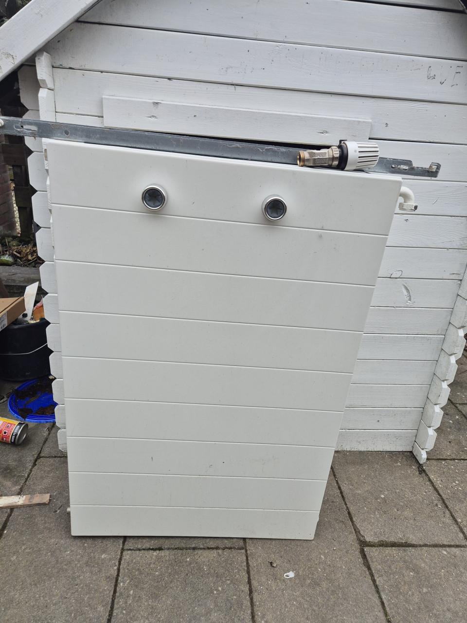 Nette radiator met ophangsysteem en thermostaatknop.