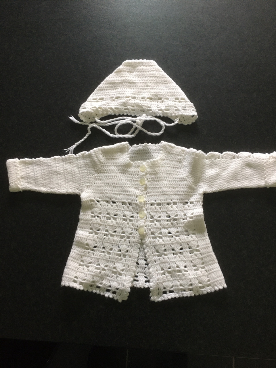 Wit gehaakte baby omslagdoek met  gehaakt  babyvestje (jasje) en mutsje