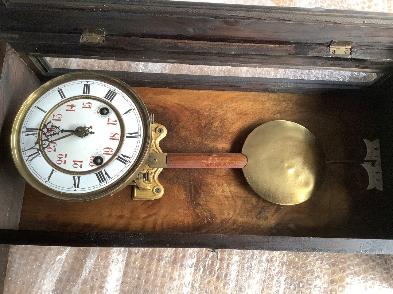 Oude, vintage hangklok met slinger en sleutel.
