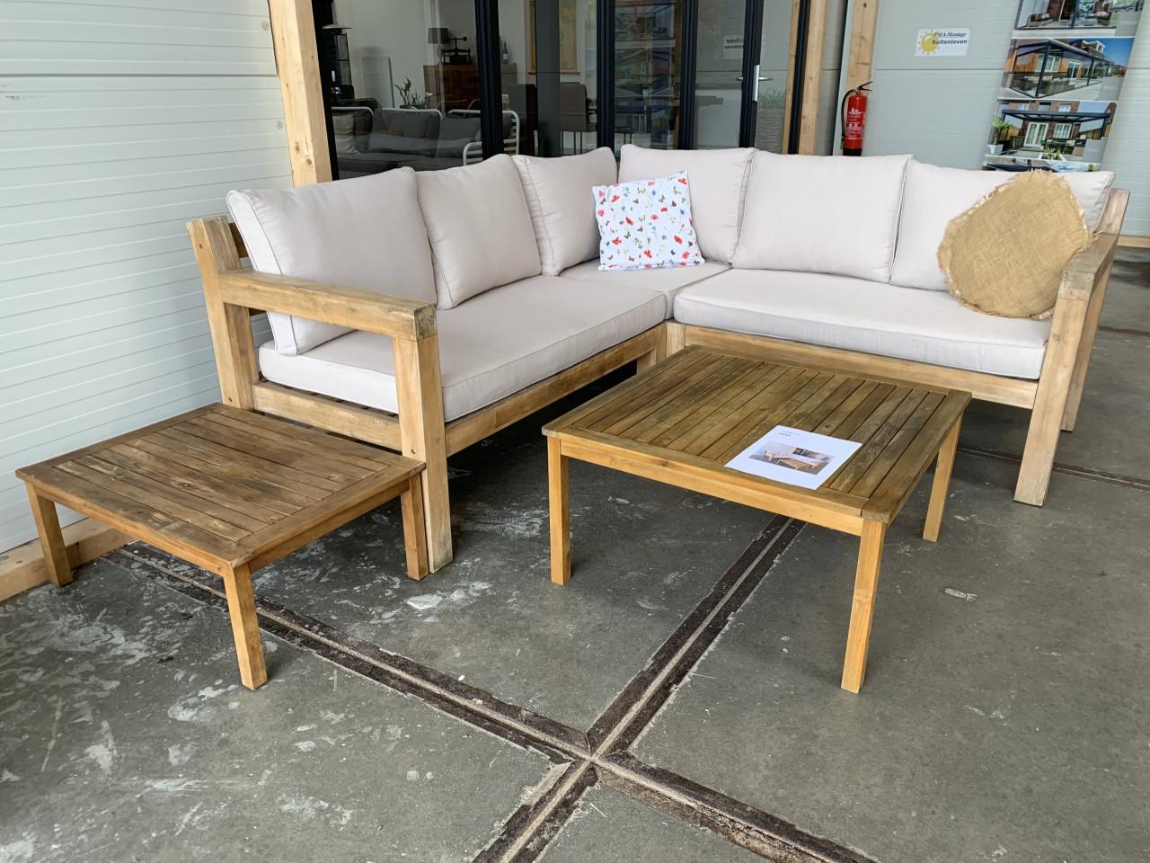 Een houten loungeset met kussens en 2 tafels, en regenhoes