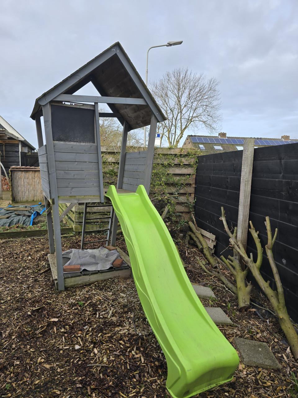 Speelhuisje met glijbaan en zandbak en houtsnippers
