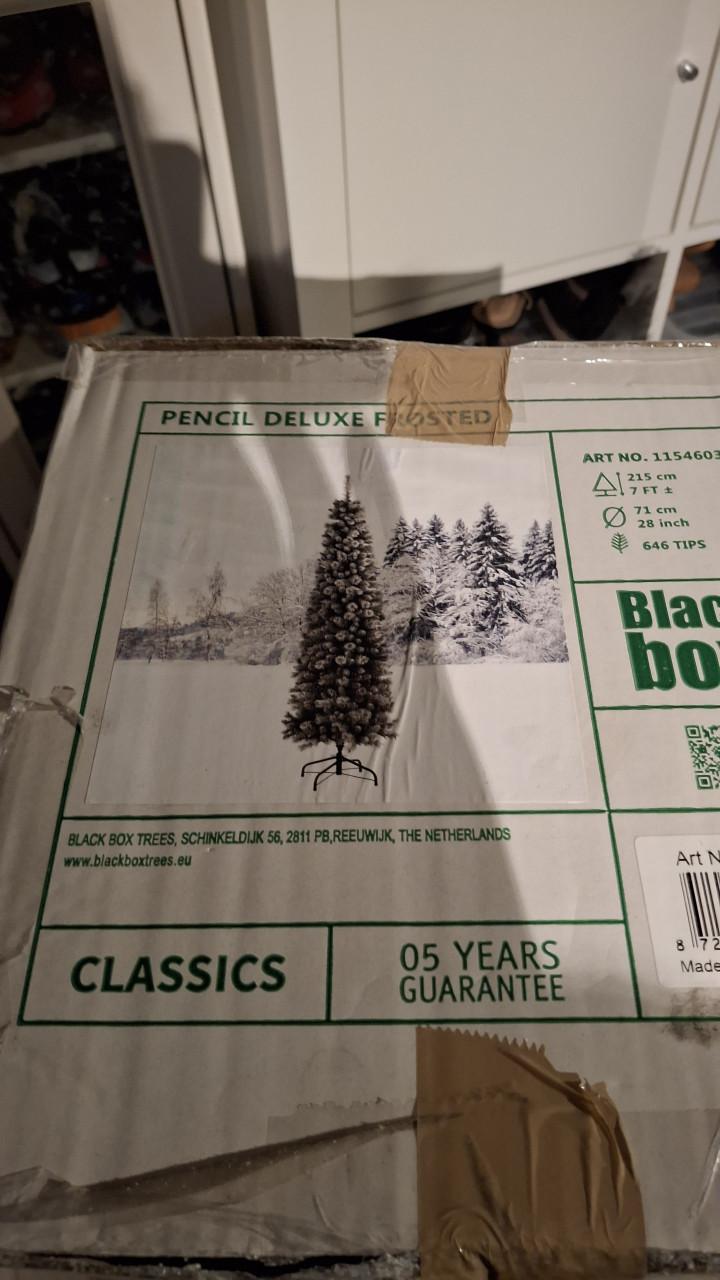 Smalle besneeuwde kerstboom met mand