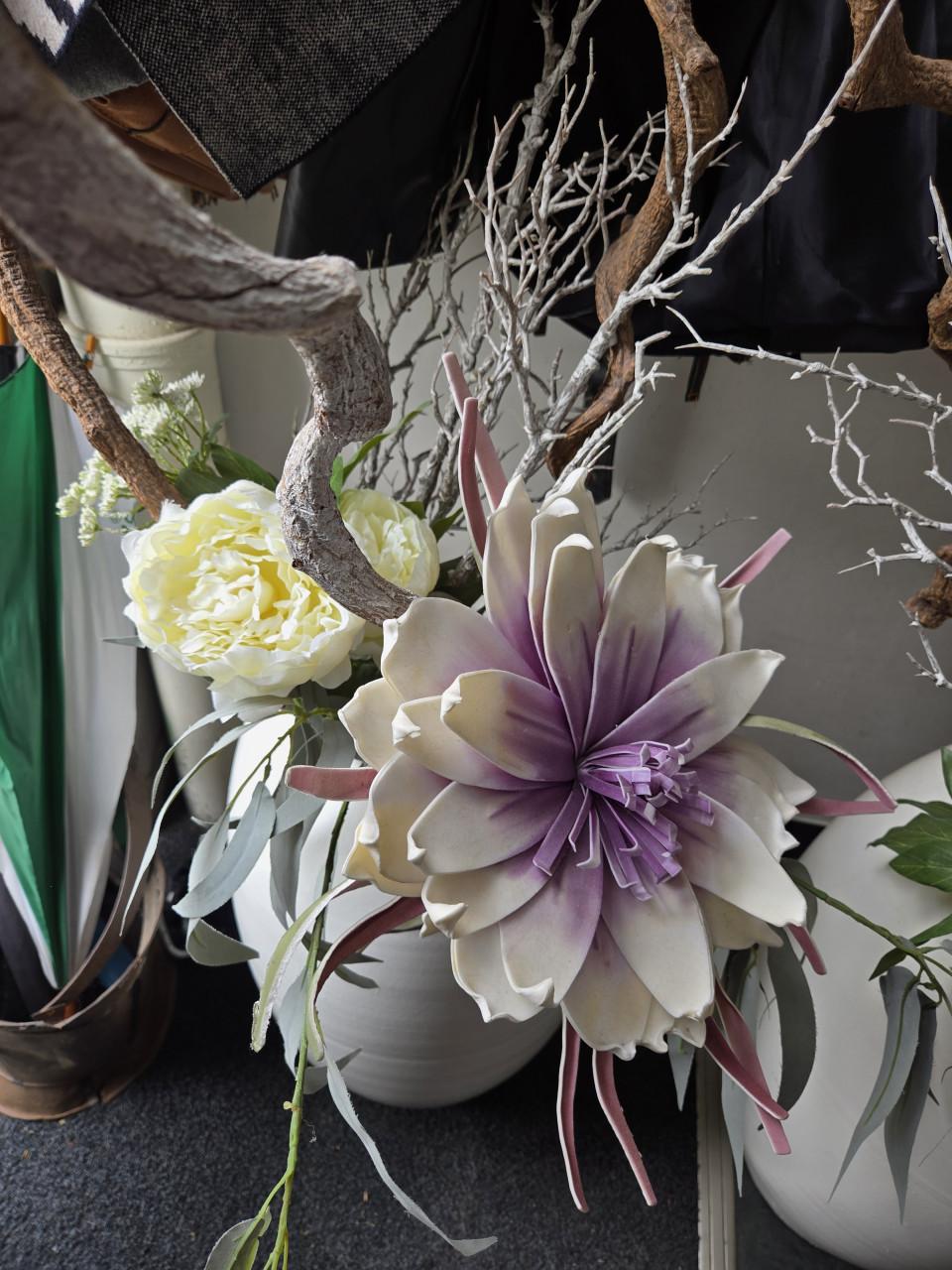 2 grote, witte vazen gevuld met decoratieve kunsttakken en kunstbloemen