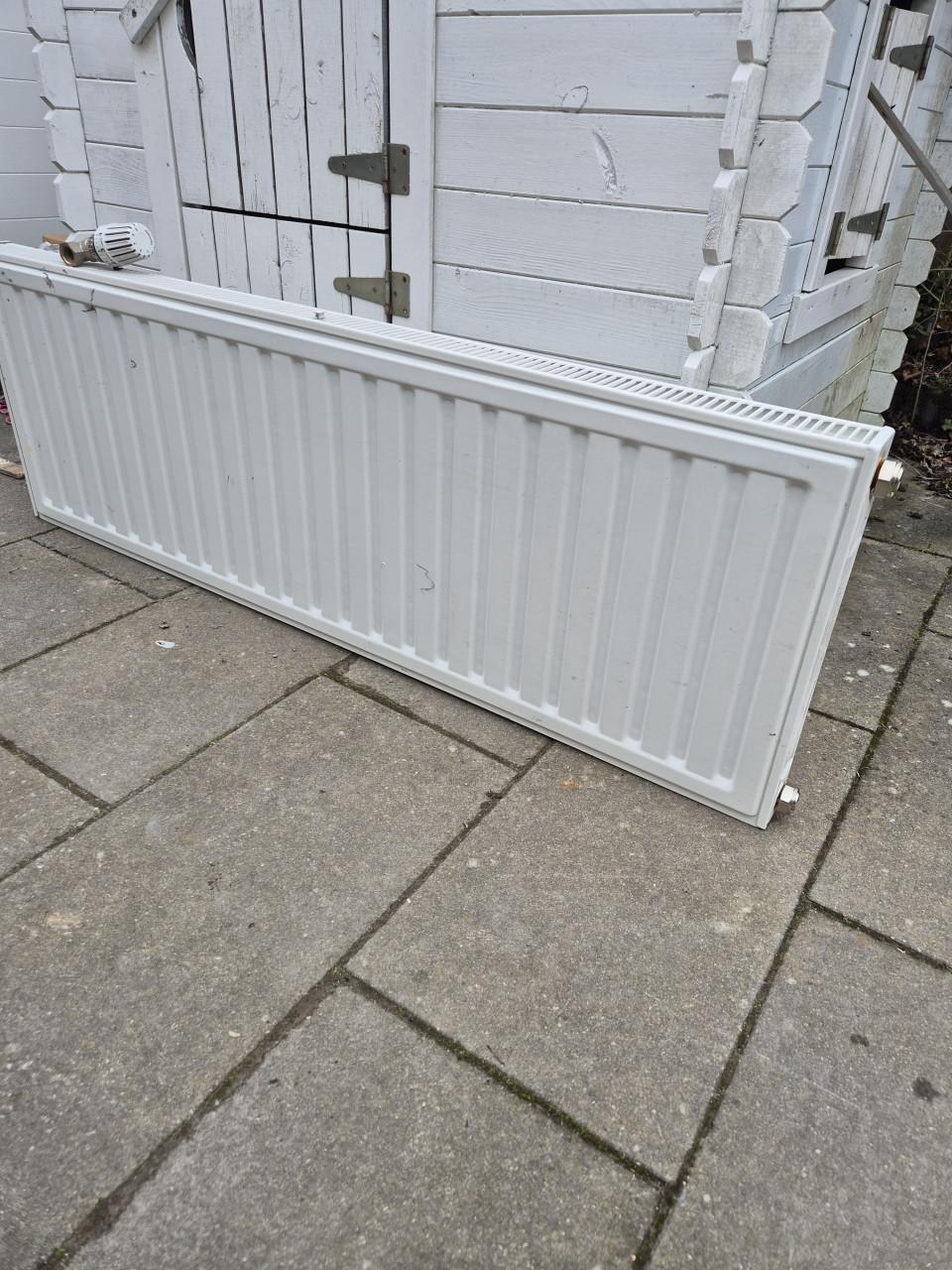 Nette radiator met ophangsysteem en thermostaatknop.