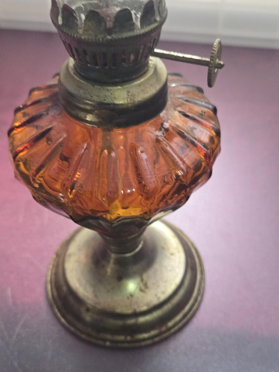 Vintage olielamp met een amberkleurige glazen voet en glazen cilinder.