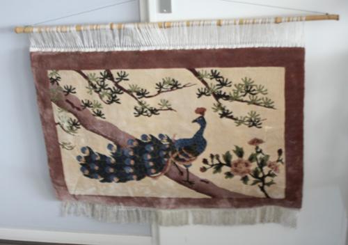 Geknoopt wandkleed met afbeelding van pauw.