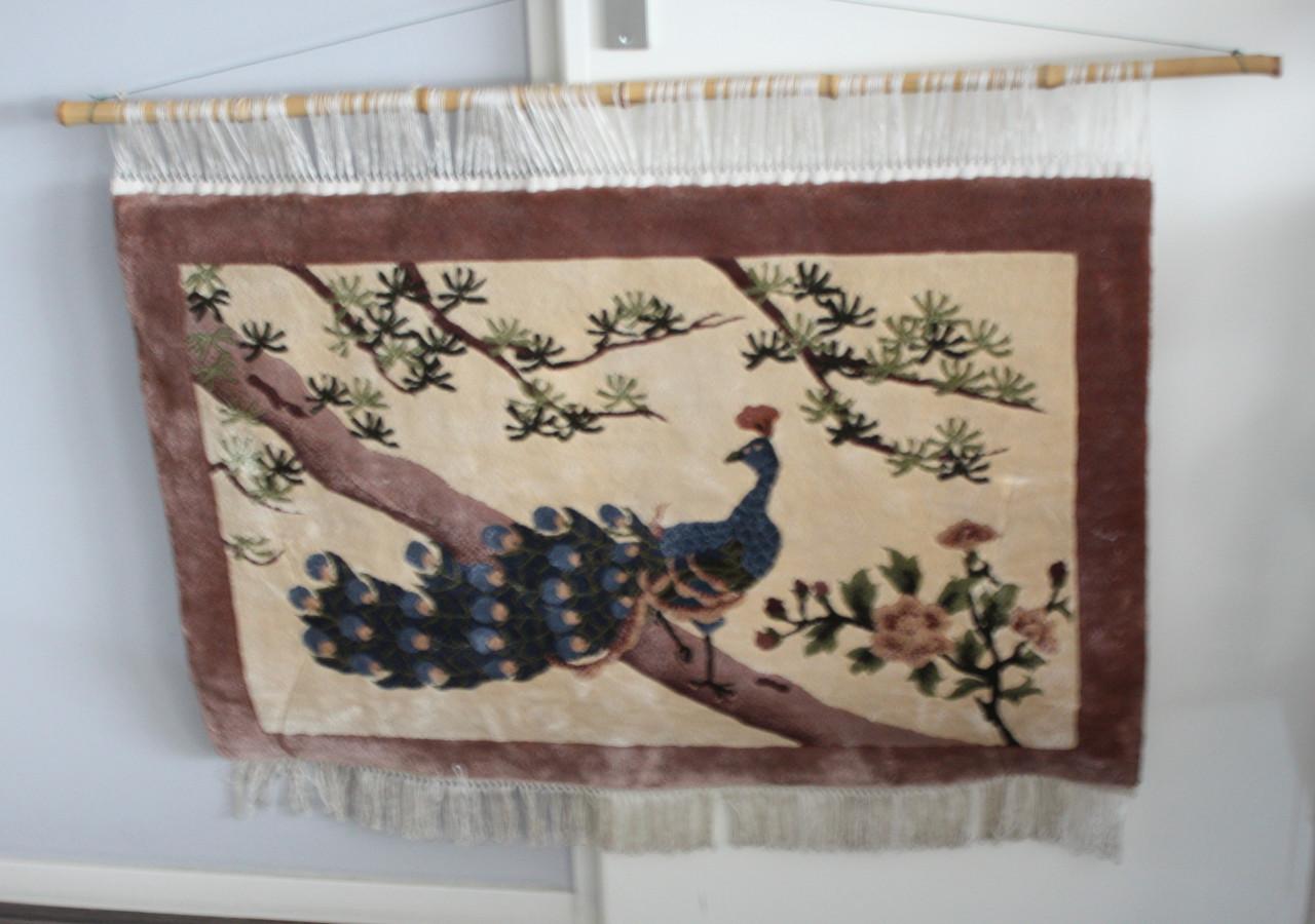 Geknoopt wandkleed met afbeelding van pauw.