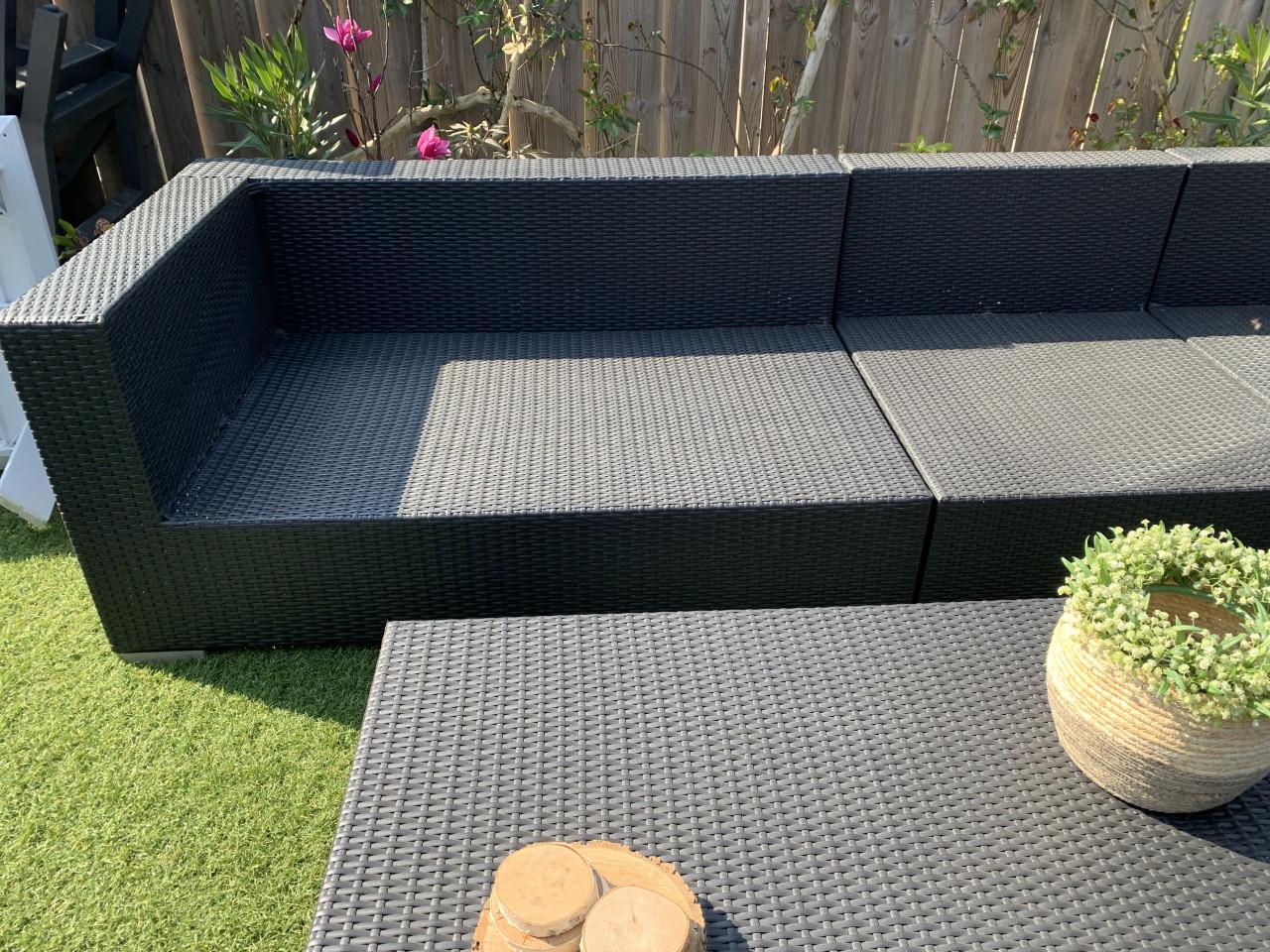 Wicker loungeset zwart met kussens en tafel.