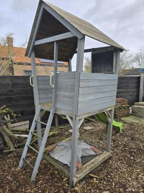 Speelhuisje met glijbaan en zandbak en houtsnippers