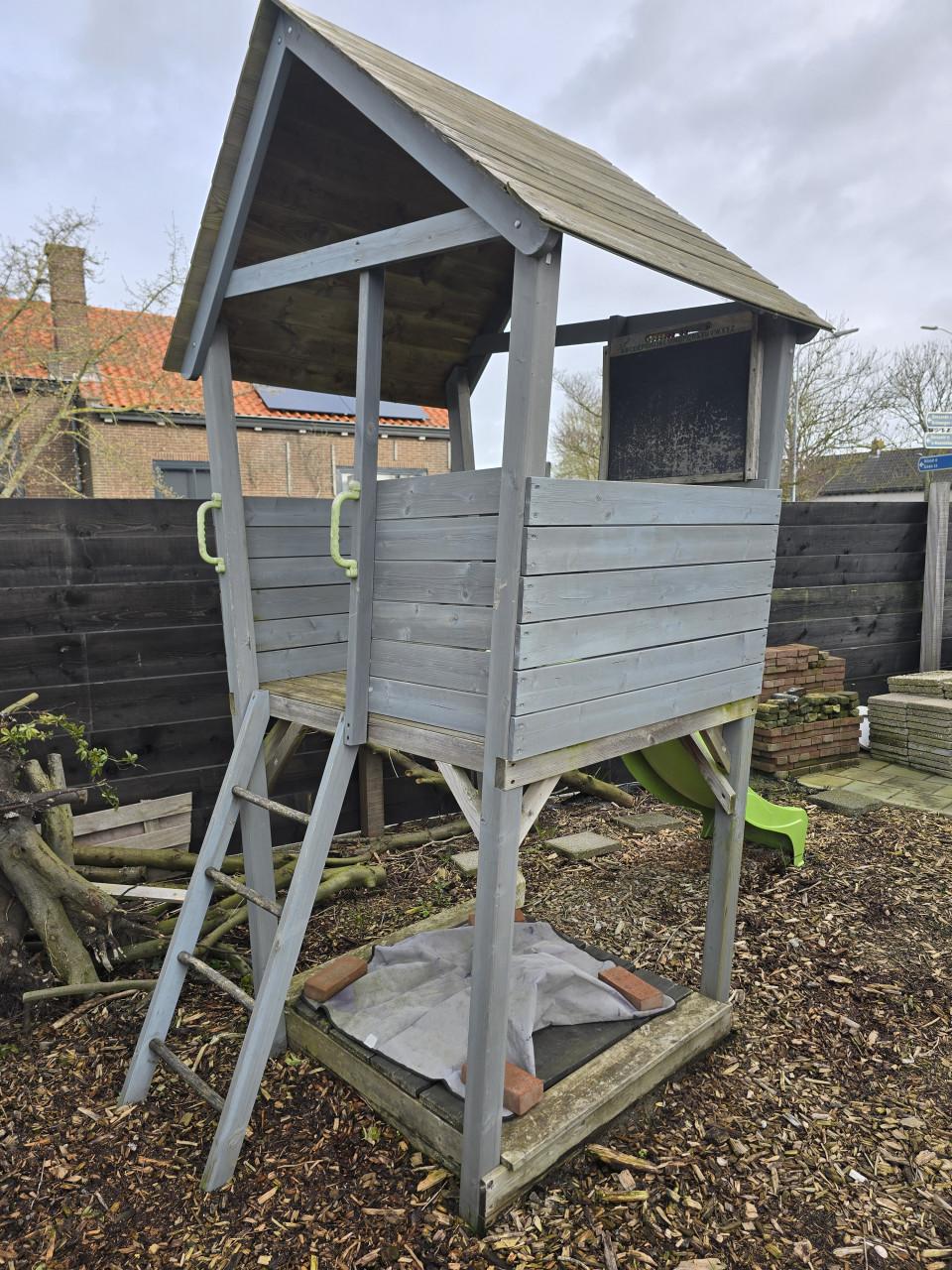 Speelhuisje met glijbaan en zandbak en houtsnippers