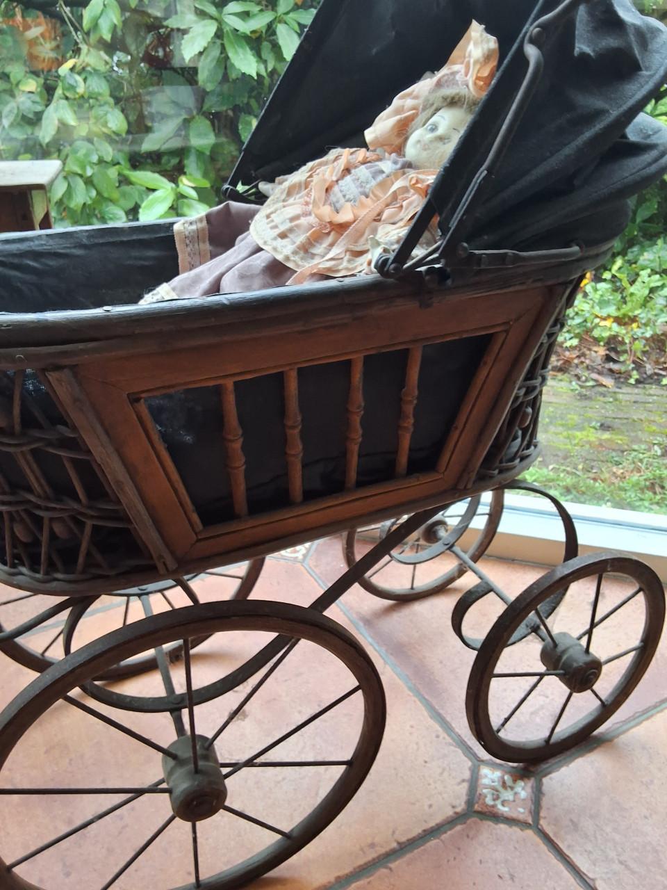 Antieke poppenwagen met porseleinen pop