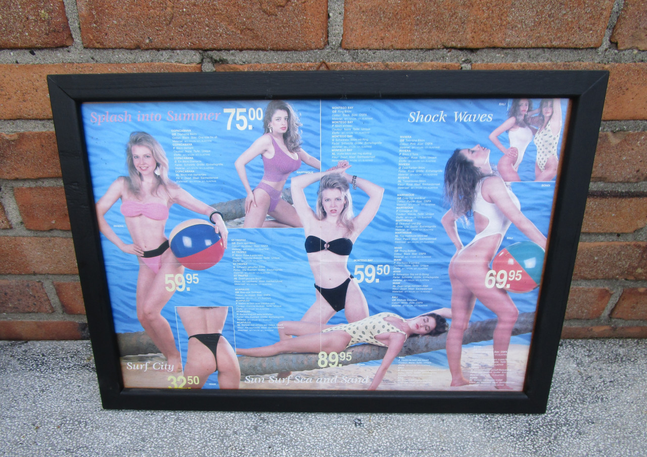 Badkleding in een zwarte lijst achter ontspiegeld glas.