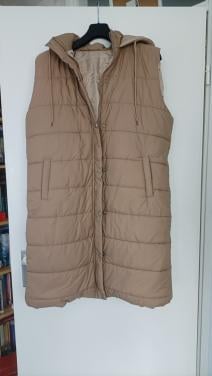Lange dikke bodywarmer met capuchon. Lichtbruin van kleur. Maat 44/46. Slui