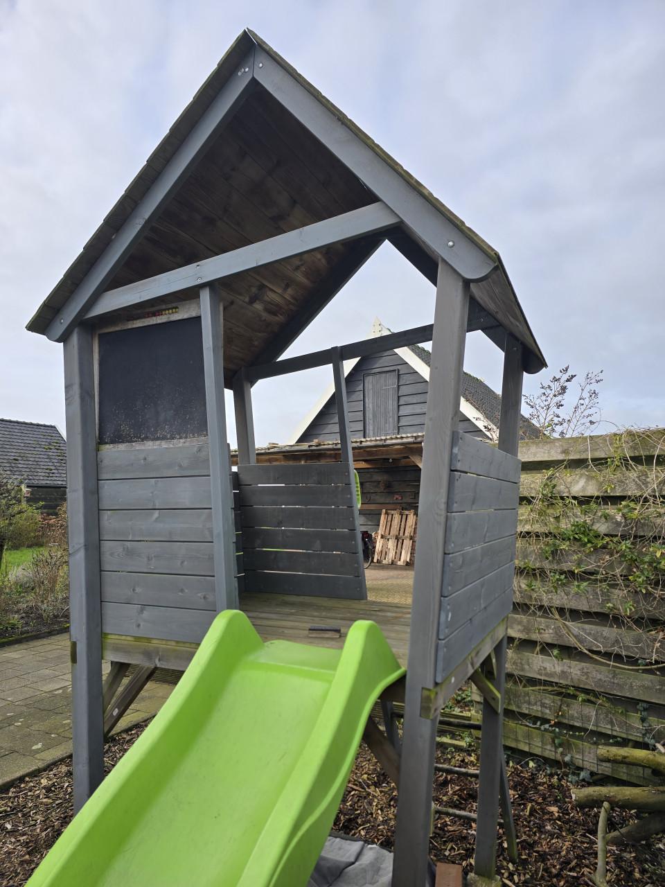 Speelhuisje met glijbaan en zandbak en houtsnippers