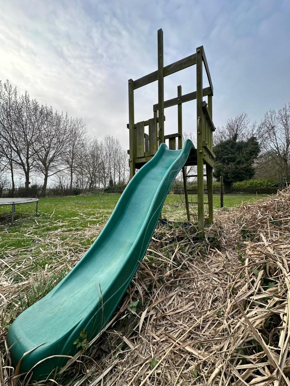 Houten speelhuisje met kunststof glijbaan.