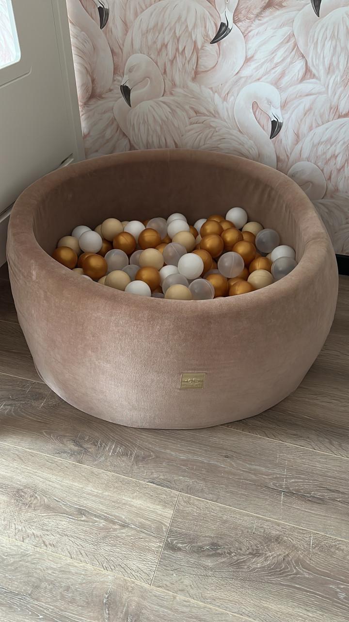 Roze fluwelen ballenbak met gouden en witte ballen