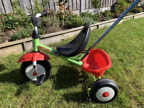 Een groene Kettler driewieler met duwstang