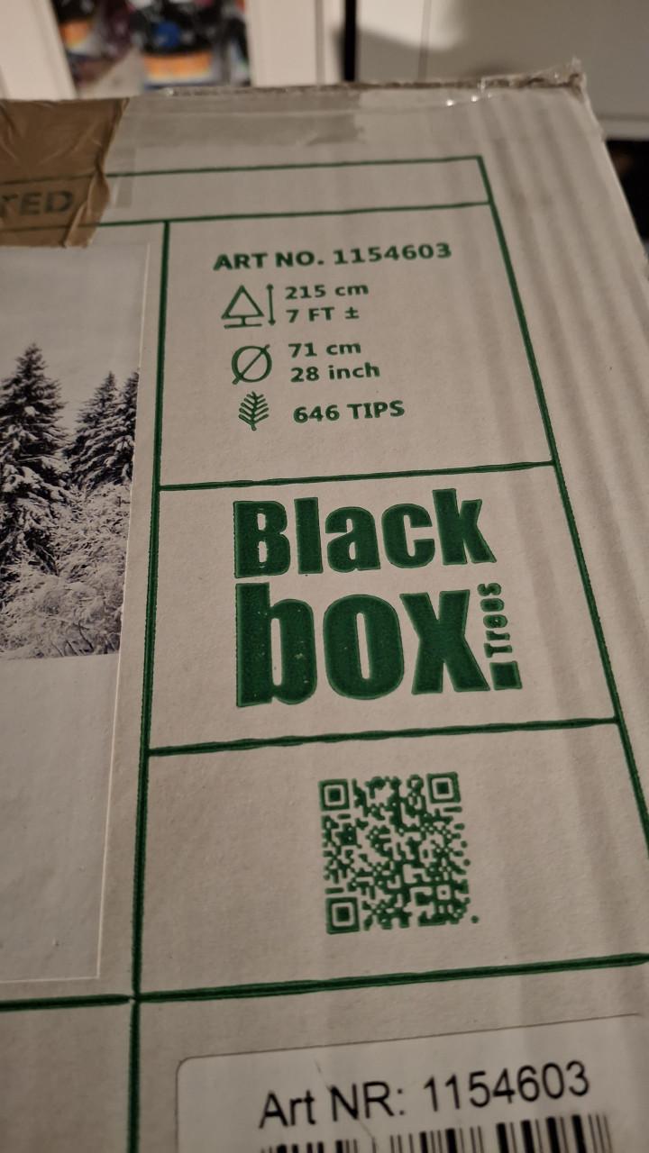 Smalle besneeuwde kerstboom met mand