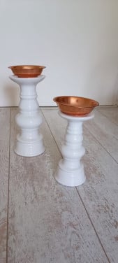 Twee witte kandelaars met koperen bakje