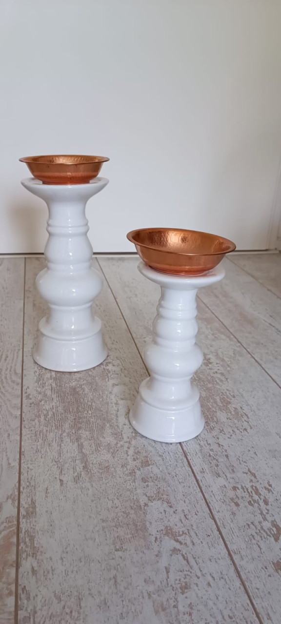 Twee witte kandelaars met koperen bakje