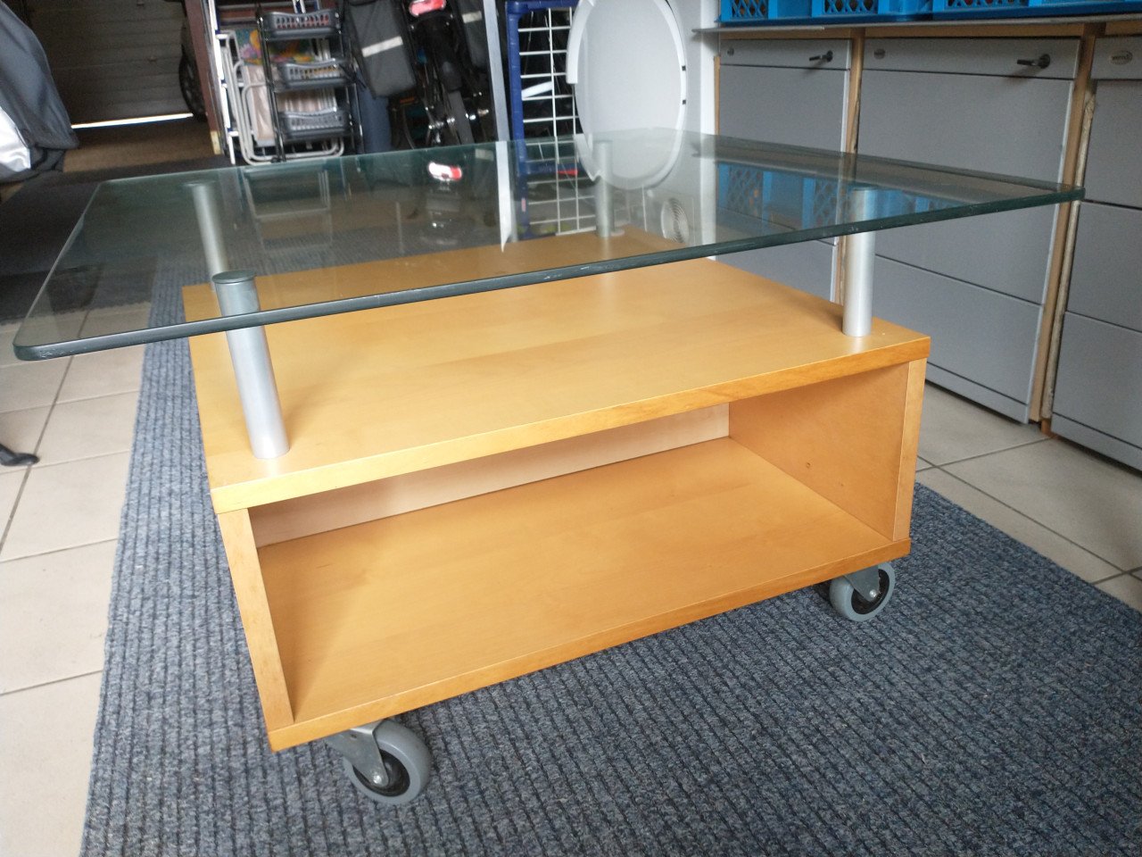 Salontafel, licht hout met hardglas en zwenkwielen.