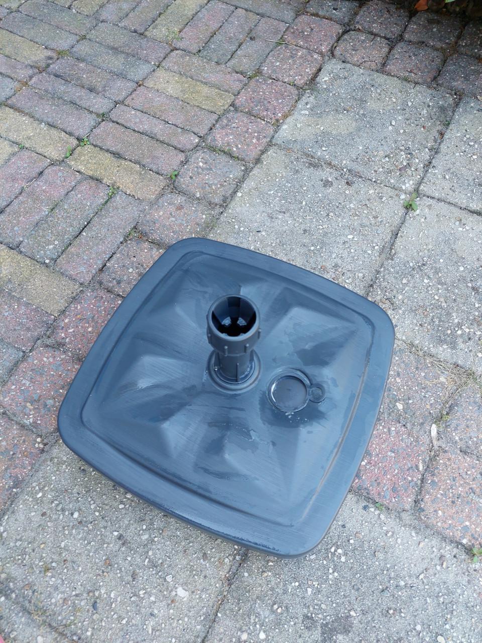 Nieuwe grijze parasolvoet met zand gevuld