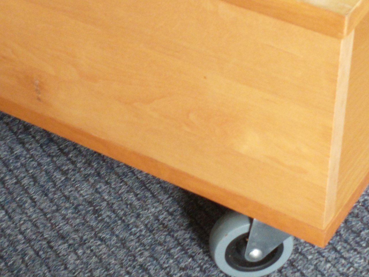 Salontafel, licht hout met hardglas en zwenkwielen.