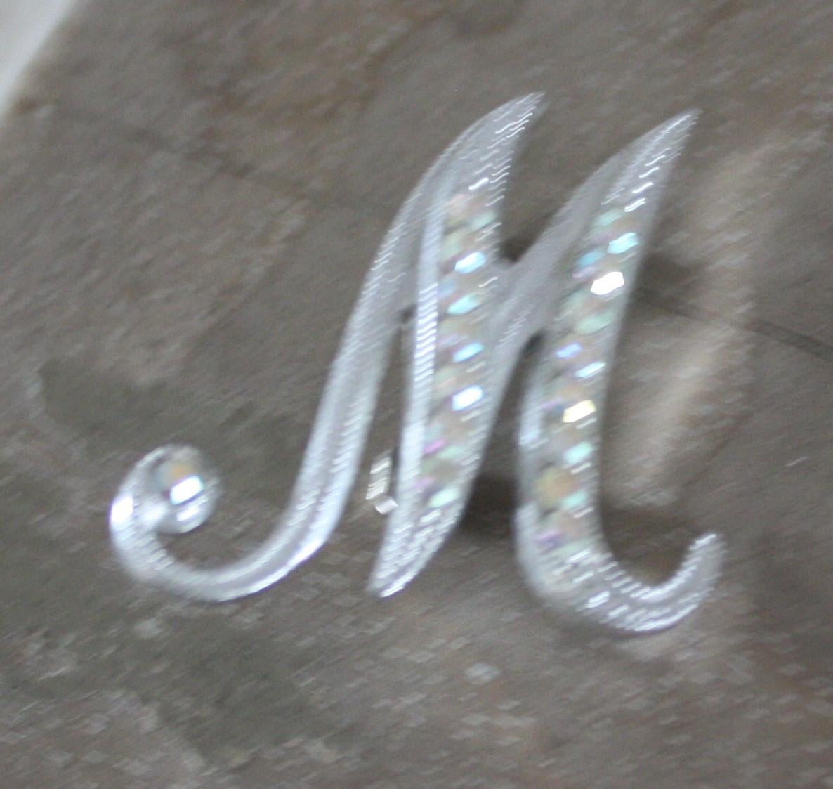 Zilverkleurige broche letter m met steentjes