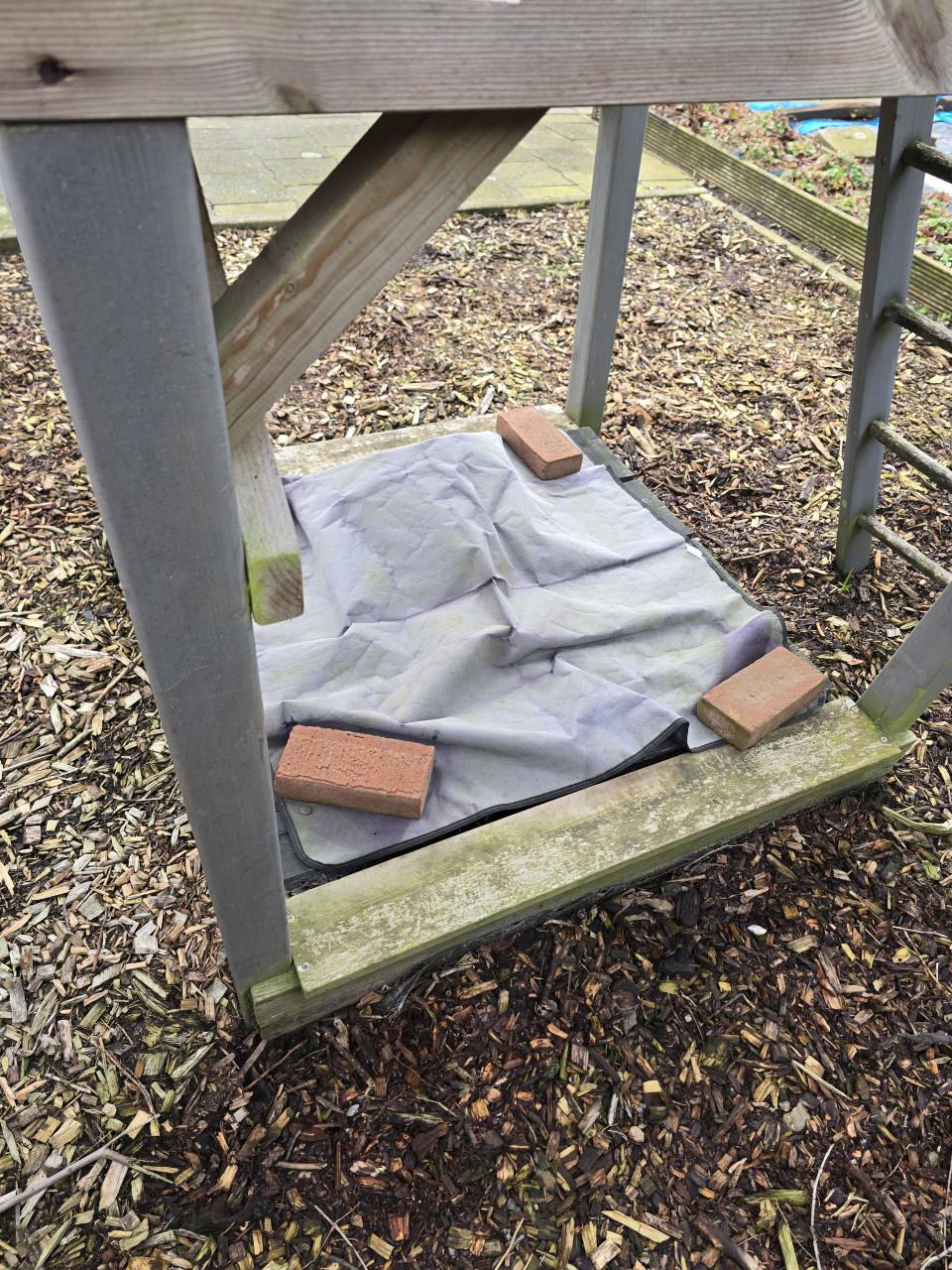 Speelhuisje met glijbaan en zandbak en houtsnippers