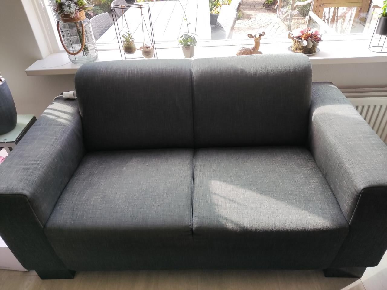 GRATIS! Comfortabele grijs/zwart 2,5 & 3 zits bank + poef