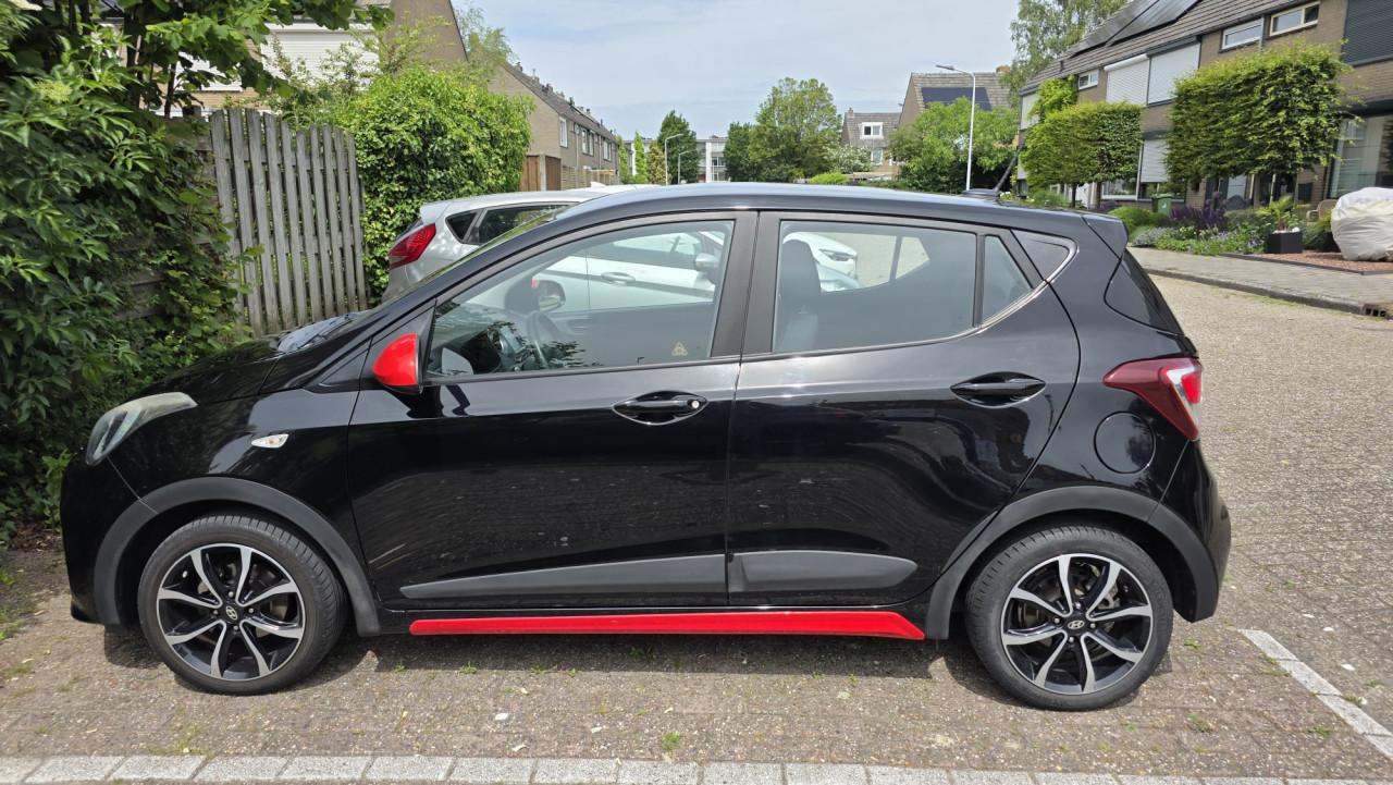 Hyundai I10 2019 met 69300 km Zwart met rode spiegels en sierstrippen.