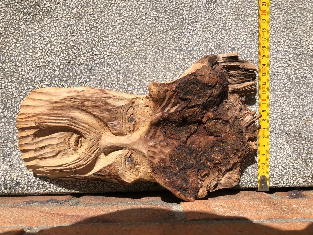 Dit is een houten wanddecoratie in de vorm van een gezicht met baard.