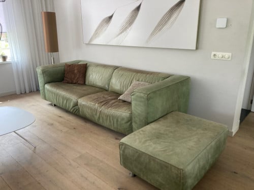 Groene leren bank met hokker