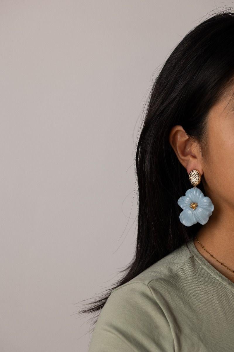 Oorbellen met blauwe bloemen en goudkleurige accenten.