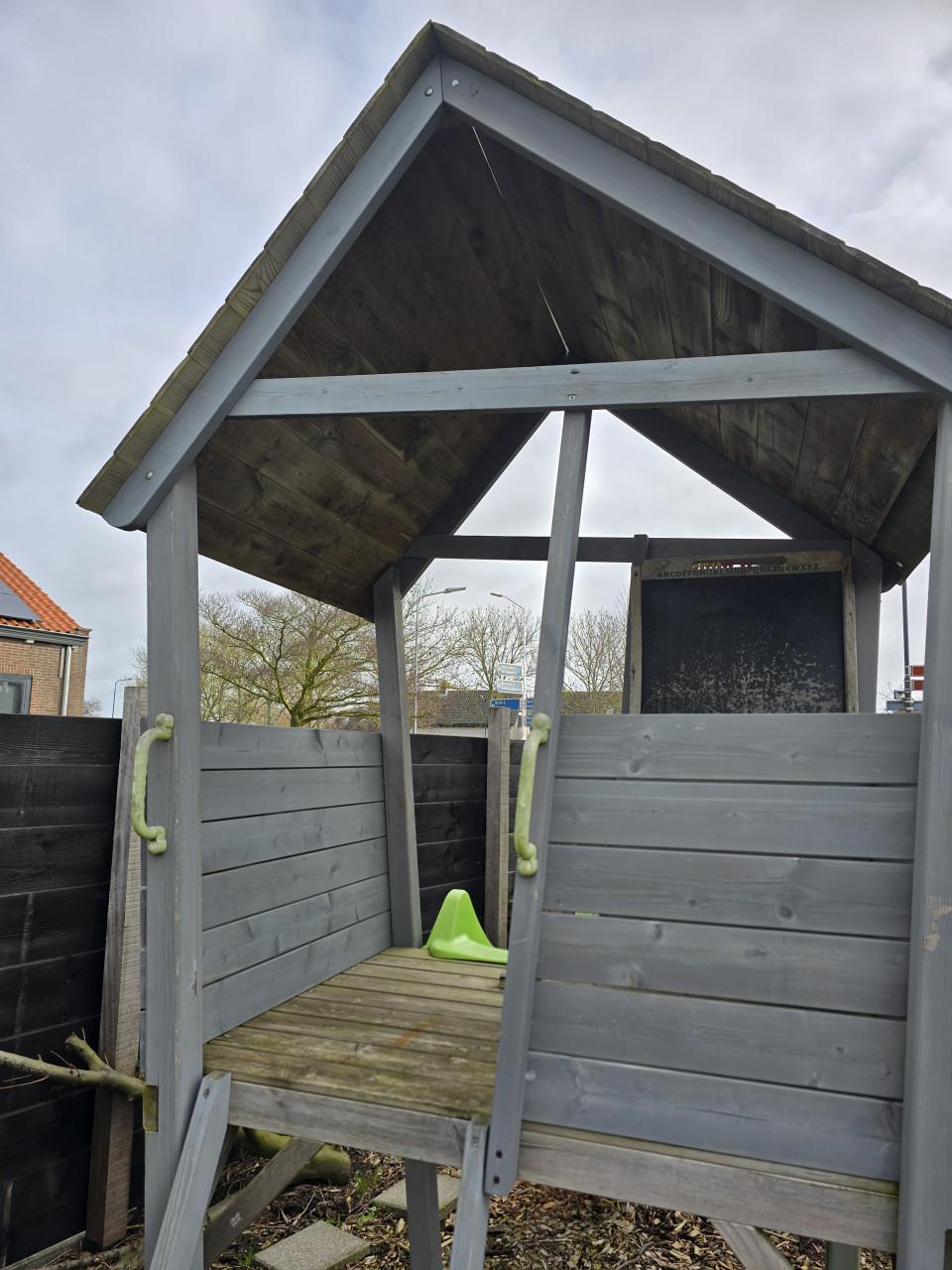 Speelhuisje met glijbaan en zandbak en houtsnippers