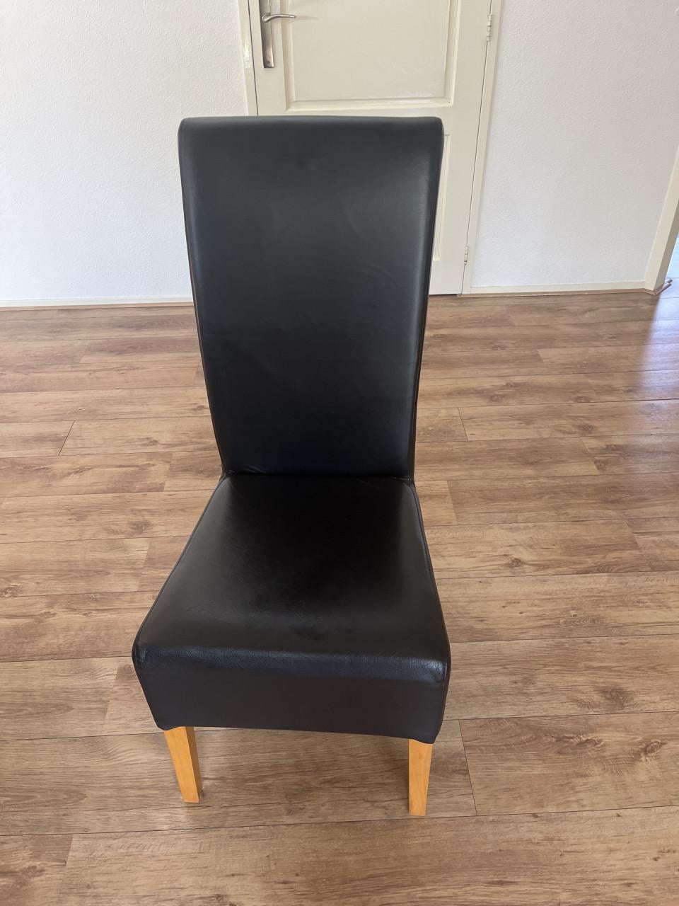 Eiken eettafel met 6 zwarte leren stoelen.