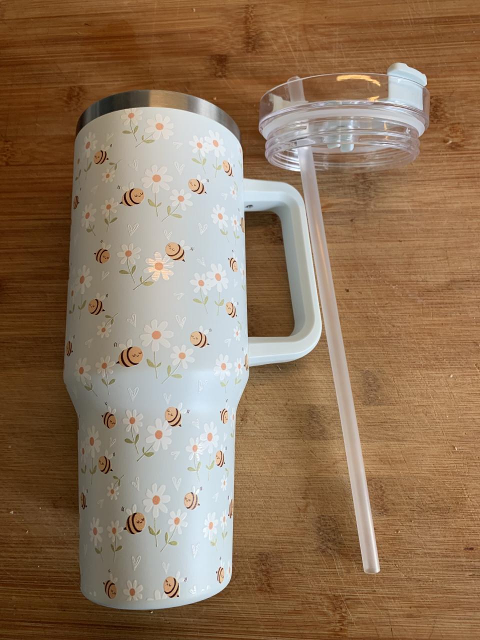 Tumbler beker heeft een vrolijke print van bijen en bloemen.