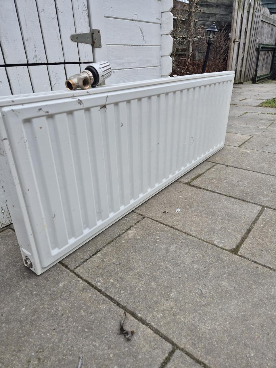 Nette radiator met ophangsysteem en thermostaatknop.