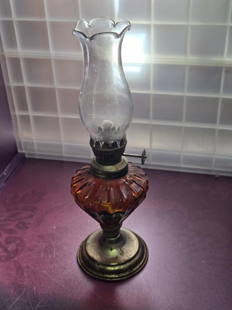 Vintage olielamp met een amberkleurige glazen voet en glazen cilinder.