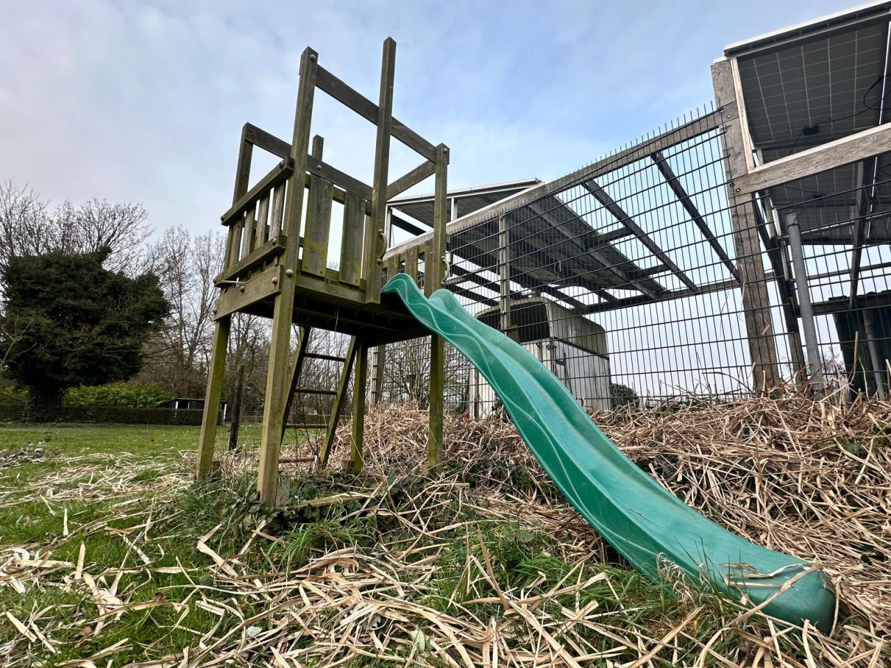 Houten speelhuisje met kunststof glijbaan.