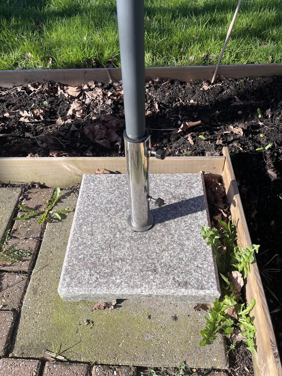 Oranje parasol met voet van steen