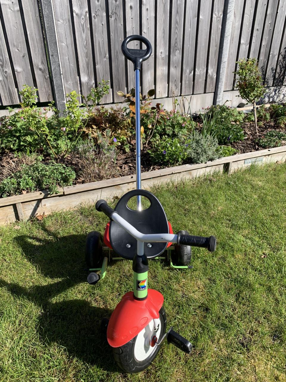 Een groene Kettler driewieler met duwstang