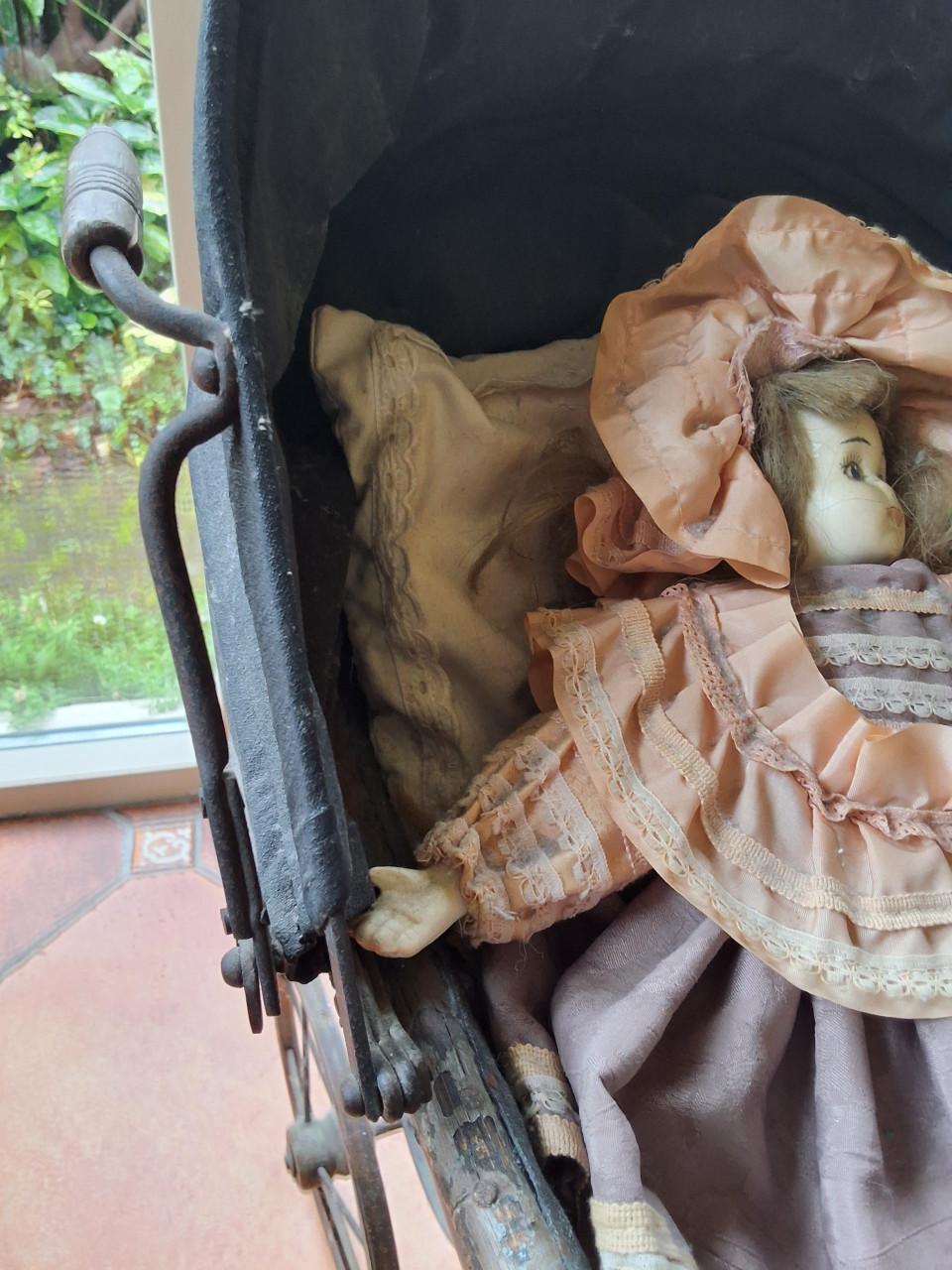 Antieke poppenwagen met porseleinen pop