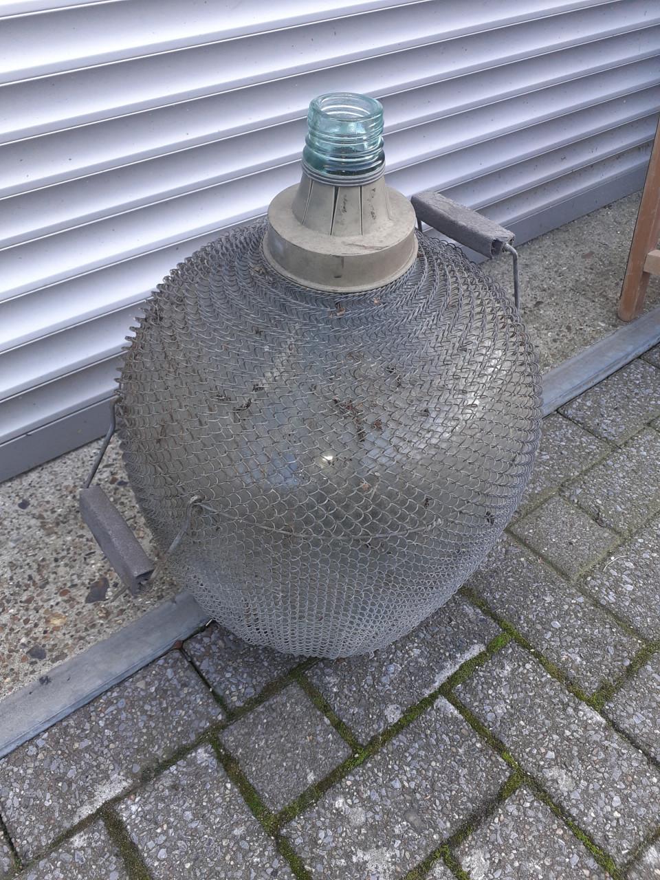 Brocante grote gistfles /wijnfles in ijzeren omhulsel spiraal
