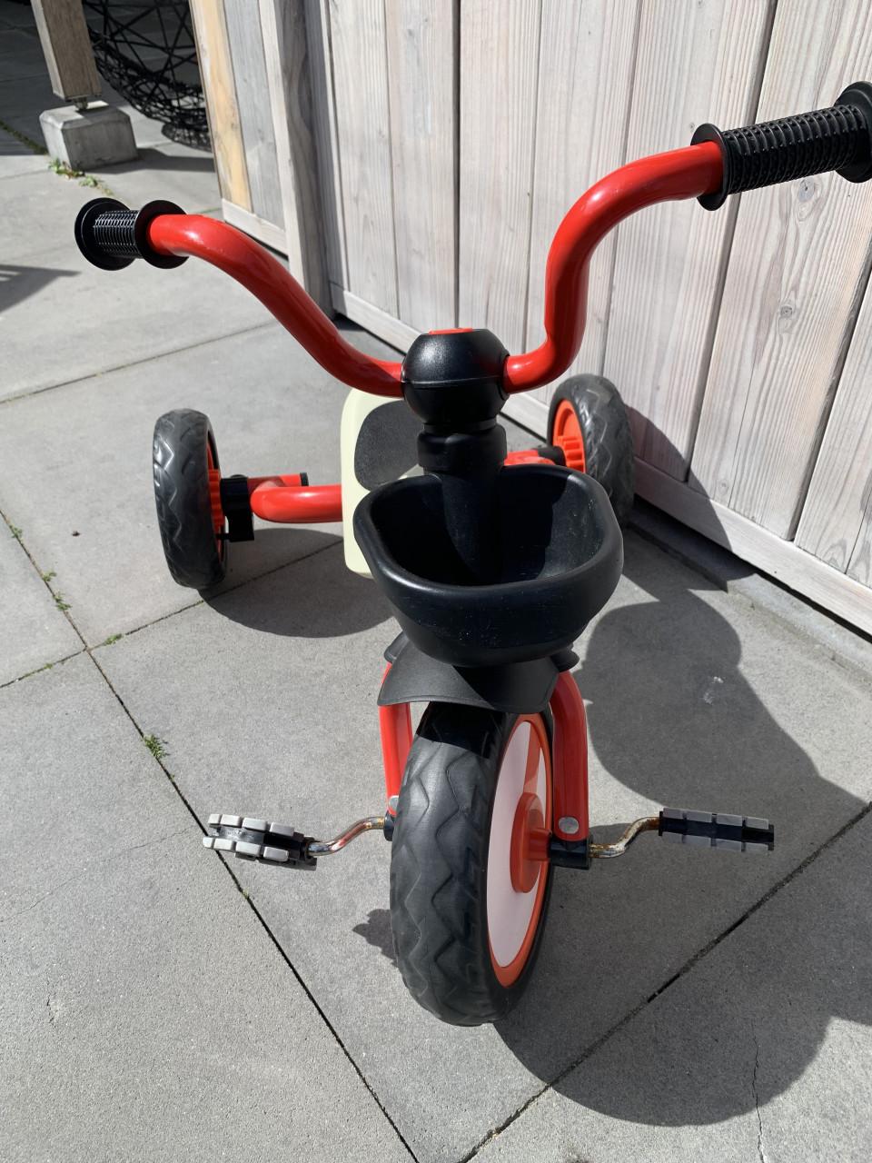 Rode driewieler met een beige zitting en zwarte handvatten