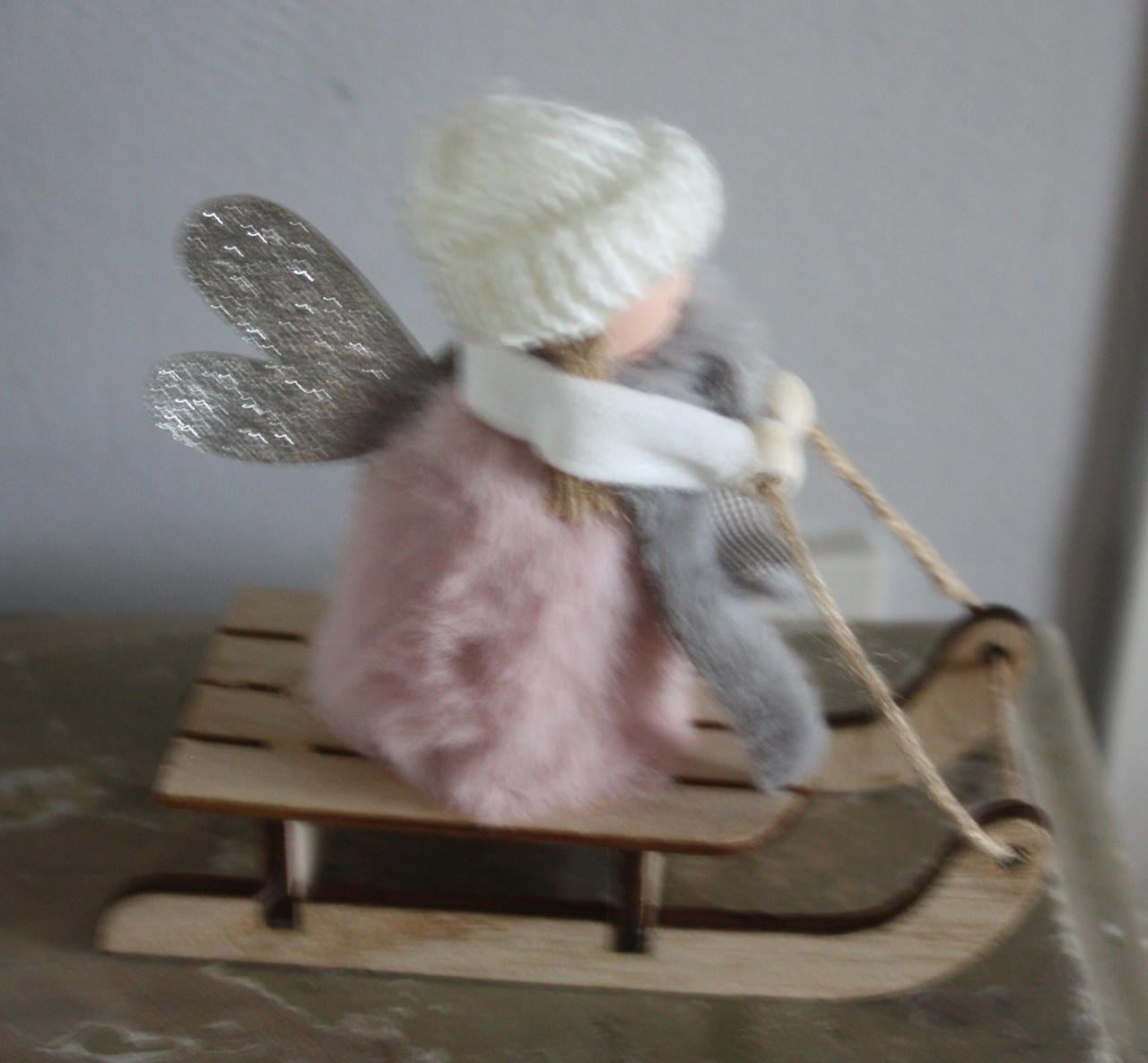 Roze stoffen popje op houten slee