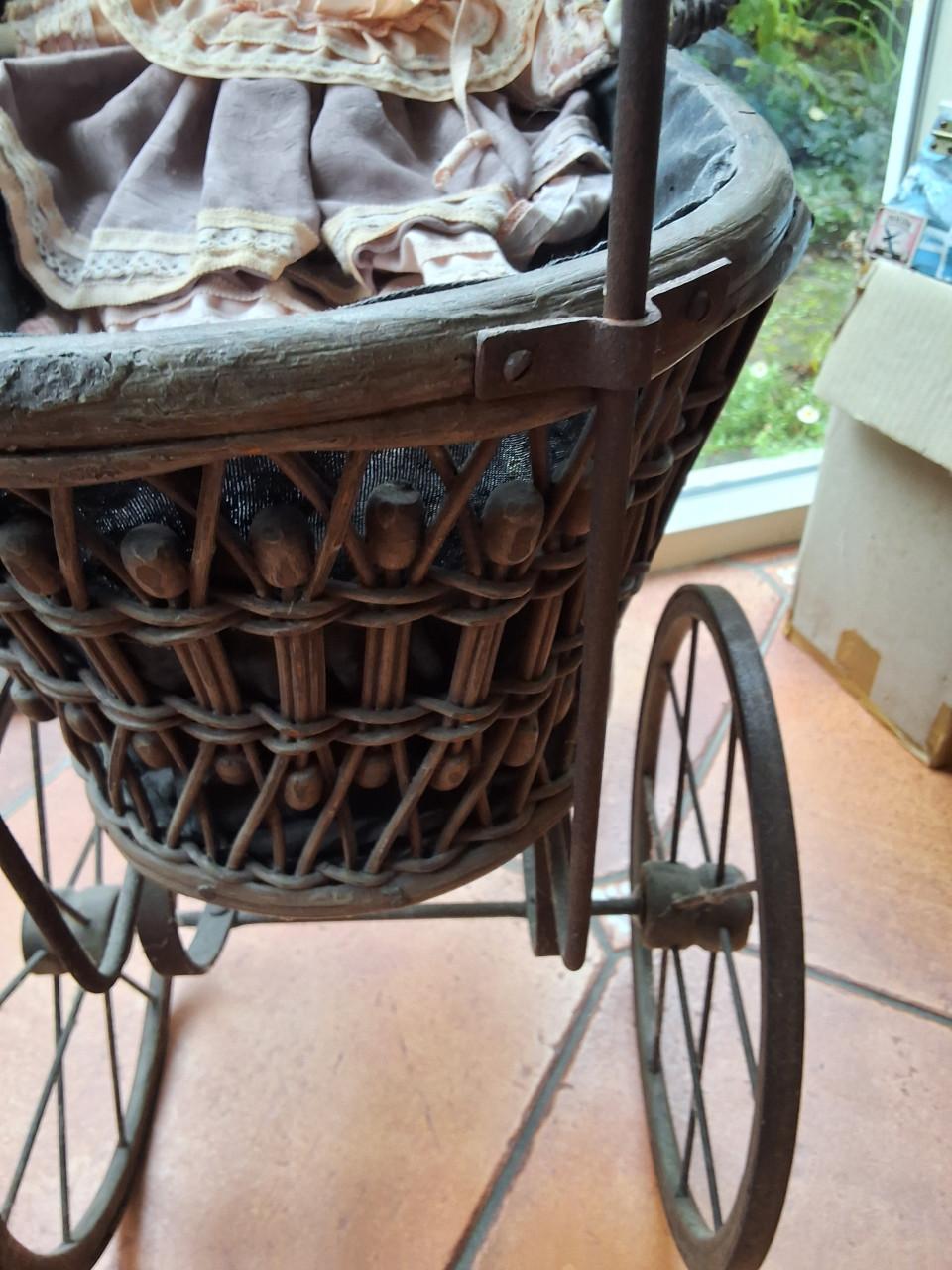 Antieke poppenwagen met porseleinen pop