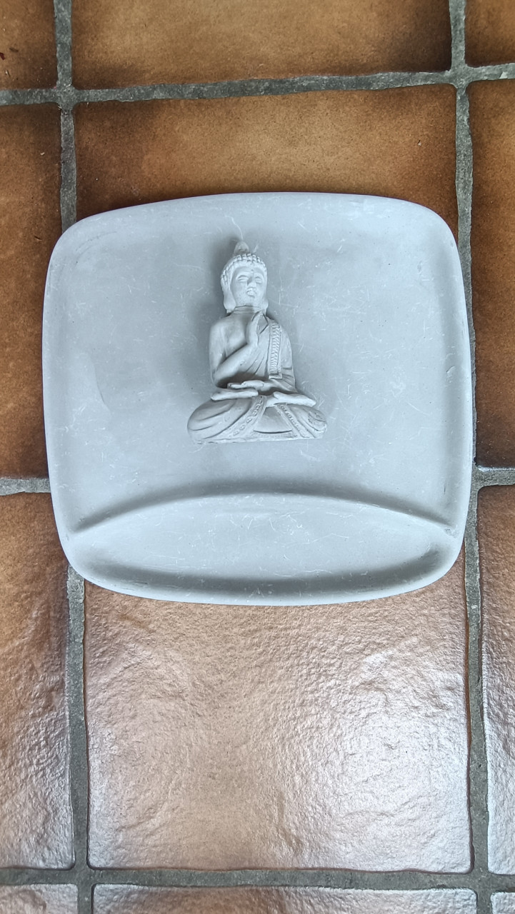 Boeddhabeeldje op een bordje / tray. Beide van gips of soort beton.